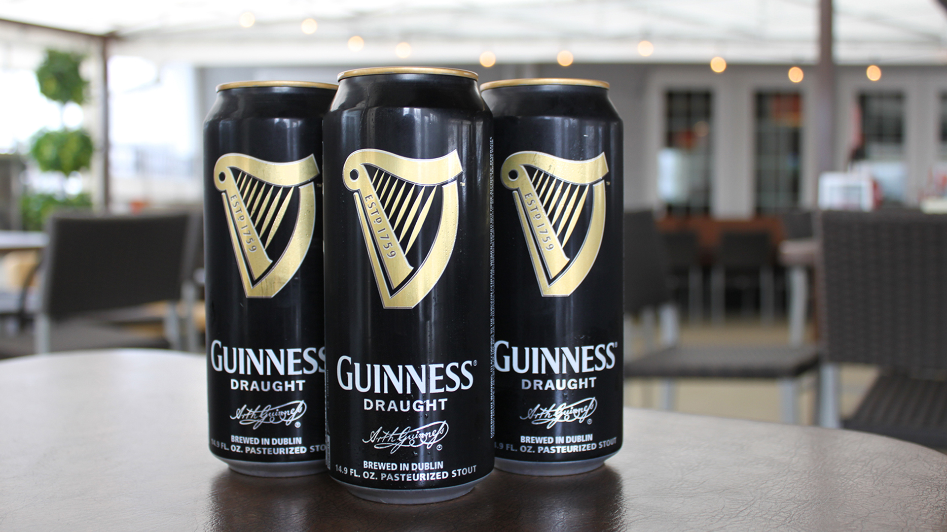 Three Guiness Cans on table.