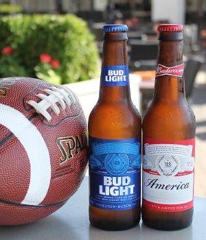 Football, Bub light, and Budweiser bottles on table.